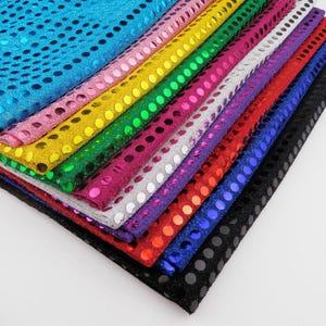 Puede incluir: Una pila de diez telas de diferentes colores con un patrón de lunares. Los colores son azul, rosa, amarillo, verde, morado, plateado, rojo, azul oscuro y negro.
