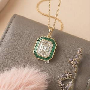 gold pendant featuring a clear emerald cut center diamond and green gemstone border.
