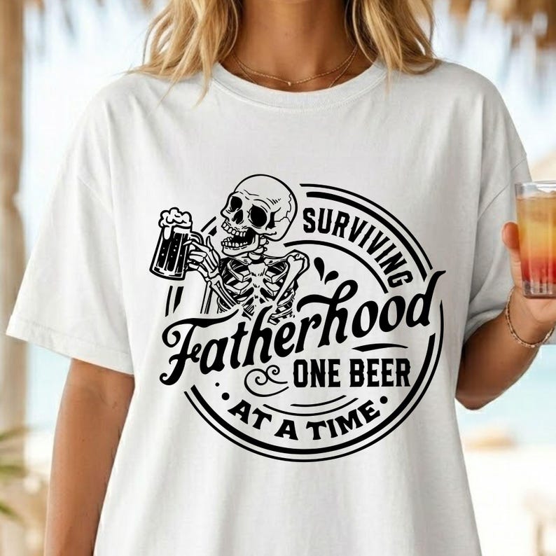 May include: White t-shirt featuring a black graphic of a skeleton holding a beer mug. The design includes the text "Surviving Fatherhood One Beer At A Time" in a circular emblem. The shirt is a casual wear item.