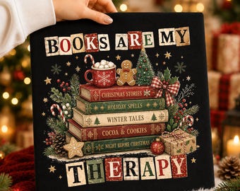 May include: A black square sign with the text BOOKS ARE MY THERAPY in block letters. The center features a stack of five books titled Christmas Stories, Holiday Spells, Winter Tales, Cocoa & Cookies, and Night Before Christmas with holiday decor.