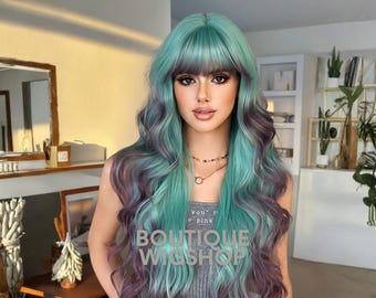 May include: A long, wavy wig in teal and purple ombre. The wig features a blunt fringe and is styled with loose curls. The text "BOUTIQUE WIGSHOP" is visible on the front of the wig.