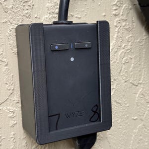 May include: A black Wyze charging station with a power cord. The station has two rectangular buttons and a small circular light. The numbers 7 and 8 are written on the station.