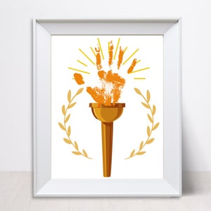 May include: A gold-colored torch with a handprint design on the top. The torch is surrounded by a laurel wreath and a sunburst.
