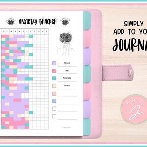 Könnte beinhalten: Ein rosa Notizbuch mit einer Seite zur Verfolgung von Angstzuständen. Der Tracker verwendet ein Raster mit farbcodierten Kästchen, um den Grad der Angst zu überwachen. Das Notizbuch enthält den Text "Anxiety Tracker" und "Simply add to your journal".