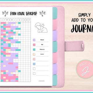 Könnte beinhalten: Ein rosa Notizbuch mit einer Seite zur Schmerzniveauerfassung. Der Tracker ist ein Raster mit farbigen Blöcken, die Schmerzlevel darstellen. Text auf der Seite enthält "PAIN LEVEL TRACKER" und "SIMPLY ADD TO YOUR JOURNAL". Das Notizbuch hat pastellfarbene Register.
