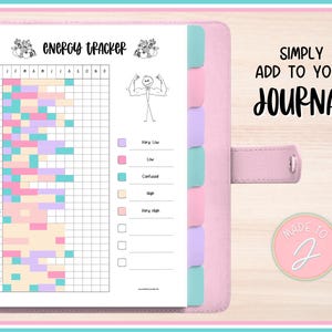 May include: A pink journal with an energy tracker page. The tracker has a grid with color-coded blocks for each day of the month. The text "ENERGY TRACKER" is at the top. The journal also has the text "SIMPLY ADD TO YOUR JOURNAL".