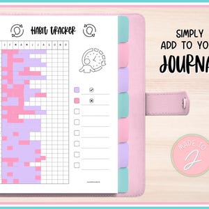 Könnte beinhalten: Ein rosa Planer mit einer Gewohnheits-Tracker-Seite. Der Gewohnheits-Tracker ist ein Raster mit Feldern für jeden Tag des Monats, gefüllt mit rosa und lila Blöcken. Auf der Seite steht "Habit Tracker". Der Planer hat auch bunte Registerkarten und den Text "Simply Add To Your Journal".