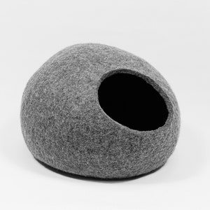 May include: A gray felt cat bed shaped like a rounded dome with a circular opening. The bed is made of a soft, fuzzy material.