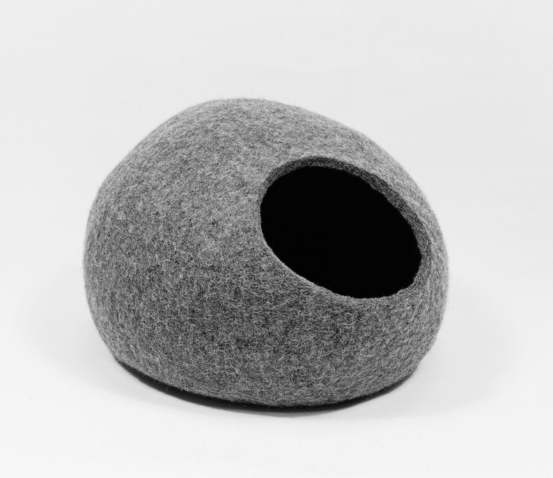 May include: A gray felt cat bed shaped like a rounded dome with a circular opening. The bed is made of a soft, fuzzy material.