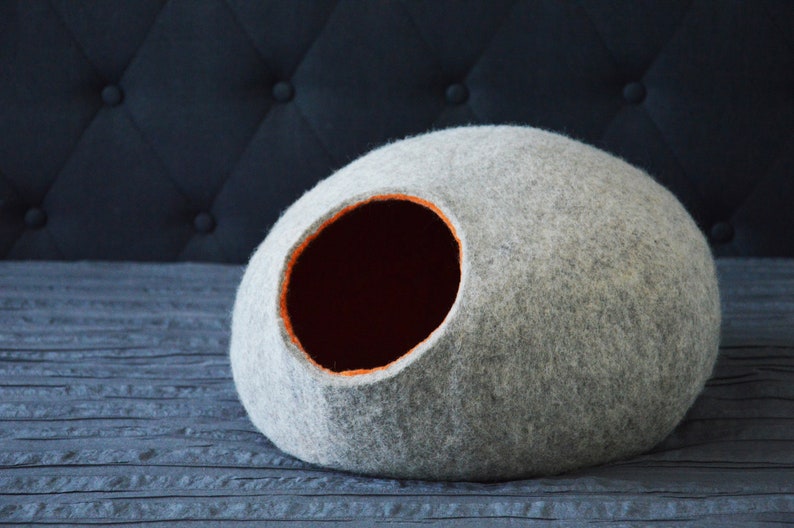 May include: A gray felt cat bed shaped like a dome with an orange felt trim around the entrance hole.