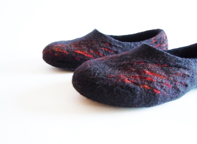 May include: A pair of dark blue felt slippers with vibrant red streaks. These cozy, handmade slippers have a rounded toe and a low-profile design, perfect for indoor wear. The felted wool provides warmth and comfort.