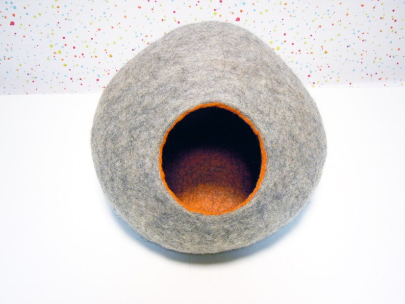 May include: A gray felt cat bed shaped like a dome with an orange felt interior.