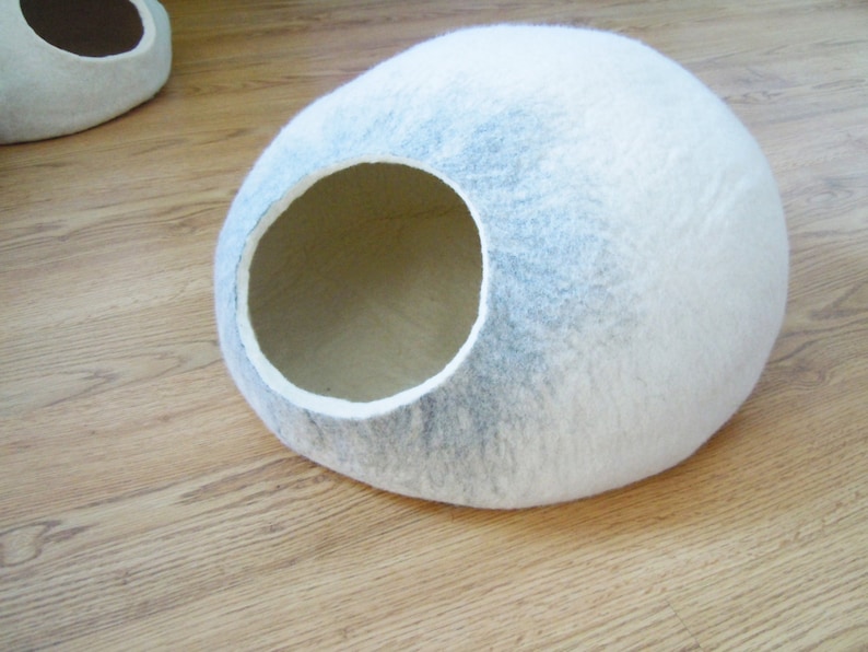 May include: A white and gray felt cat bed shaped like a dome with a round entrance hole.