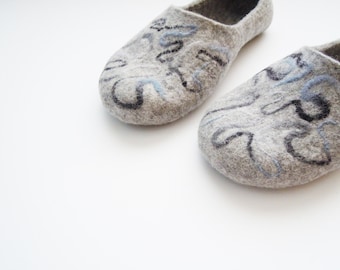 May include: A pair of gray felt slippers with blue and black abstract designs. The slippers are soft and comfortable, perfect for keeping your feet warm in the winter.