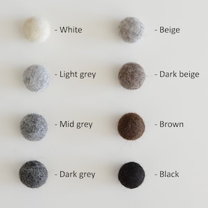 May include: Eight felt balls in different colors: white, beige, light grey, dark beige, mid grey, brown, dark grey, and black. Each ball is labeled with its color.