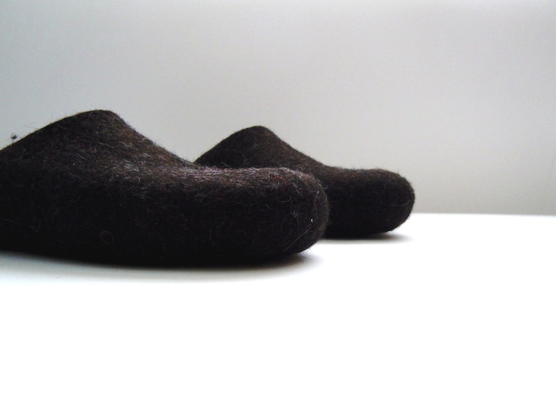 Peut inclure: Une paire de pantoufles en feutre noir. Les pantoufles sont faites d'un mat&eacute;riau doux et duveteux et ont une pointe arrondie.