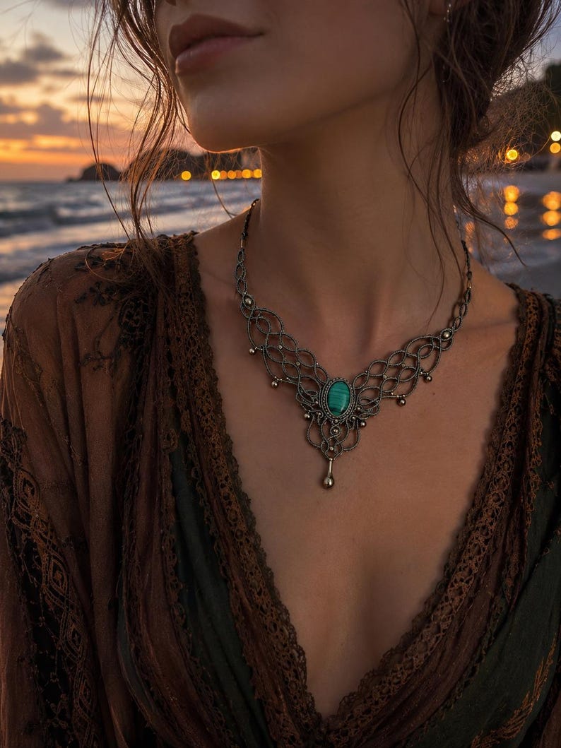 Peut inclure: Un collier compos&eacute; d'une pierre ovale centrale en malachite verte sertie dans une monture en fil m&eacute;tallique sombre avec des motifs en treillis complexes et de petites perles m&eacute;talliques pendantes, attach&eacute; &agrave; une cha&icirc;ne en m&eacute;tal sombre.