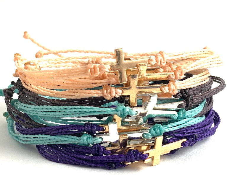colors shown are blush peach with a gold cross, charcoal black with a silver cross, mint with silver cross and purple with gold cross.