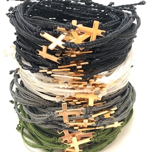Cross bracelets shown in black, white, dark grey, and olive green with gold crosses.