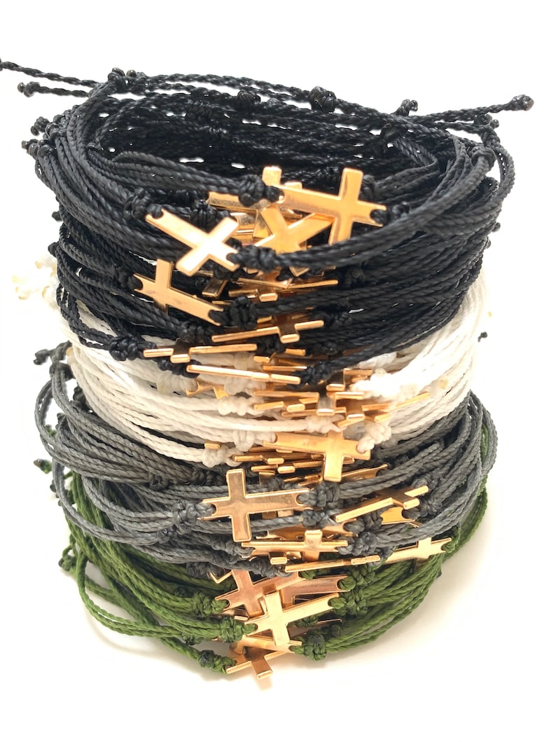 Cross bracelets shown in black, white, dark grey, and olive green with gold crosses.
