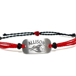 May include: Red and black braided bracelet with a silver charm that says "ALLISON" and has a volleyball with flames behind it.