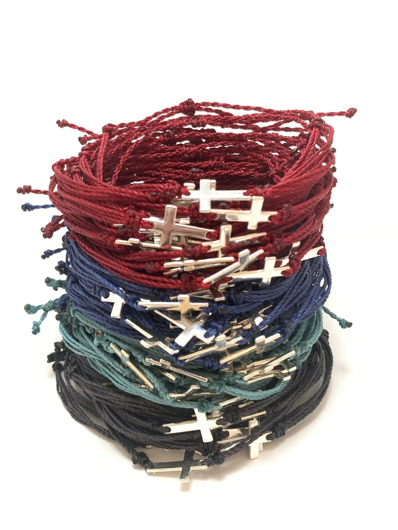 Cross bracelets shown in burgundy, navy blue, steel blue and black with silver crosses.