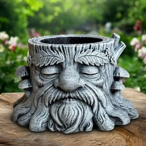 May include: A gray, tree stump-shaped planter with a carved face, closed eyes, and a long beard. The planter has a textured surface and is decorated with leaves and mushrooms. The planter is made of a durable material and is suitable for outdoor use.