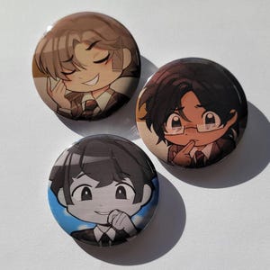 May include: Three circular badges featuring anime-style character illustrations. Each badge displays a different character in a suit, with varied hairstyles and expressions. The badges are likely for decorative use, set against a white backdrop.
