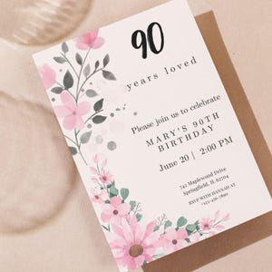 Op de afbeelding: Een rechthoekige uitnodigingskaart met de tekst 90 years loved, Mary's 90th Birthday, June 20, 2:00 PM, 742 Maplewood Drive, Springfield, IL 62704 en RSVP with Hannah at 123-456-7890, versierd met roze bloemen en grijze bladeren.