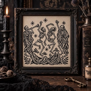 Può includere: Un ricamo a punto croce incorniciato con un disegno in filo nero su sfondo in tessuto beige. L'opera raffigura quattro scheletri che danzano e suonano una tromba, circondati da piccole forme a stella e fogliame, racchiusi in una cornice scura.