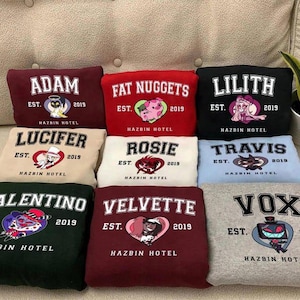 May include: A collection of nine sweatshirts in various colors, each featuring a different character name in white block letters. Each sweatshirt has a graphic and the text "EST. 2019 HAZBIN HOTEL".