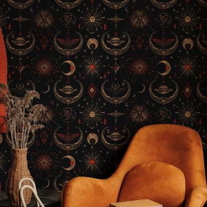 May include: An interior scene featuring a black wallpaper with a celestial pattern of moons, suns, and eyes. An orange armchair with a book sits in front of the wallpaper. A green tote bag and a vase with dried flowers are also visible.
