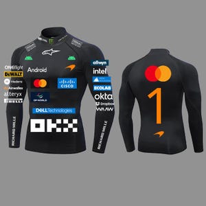 以下が含まれることがあります： Android、Cisco、Dell Technologies、OKX、Mastercardなどの多数のスポンサーロゴが入った黒の長袖コンプレッションシャツ。前面には様々なブランド名が記載され、背面には大きなオレンジ色の数字の1がプリントされています。