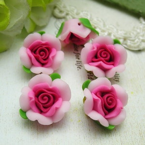 May include: Six pink and white polymer clay roses with green leaves. The roses are approximately 1 inch in diameter.