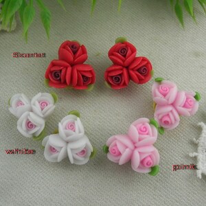 May include: Three sets of polymer clay earrings, each with three roses. The sets are in scarlet, white, and pink.