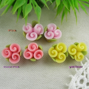 Puede incluir: Cuatro abalorios de flores de arcilla polimérica hechos a mano en rosa, rosa coral y amarillo. Cada abalorio presenta tres flores en flor con una base de hoja verde.