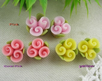 Pode incluir: Quatro pingentes de flores de argila polimérica feitos à mão em rosa, rosa coral e amarelo. Cada pingente apresenta três flores em flor com uma base de folha verde.