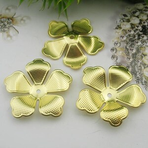 May include: Three gold metal flower-shaped embellishments with a textured surface. Each flower has five petals and a hole in the center.