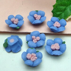 May include: A set of ten blue and pink flower embellishments. The flowers are made of polymer clay and have a realistic appearance.
