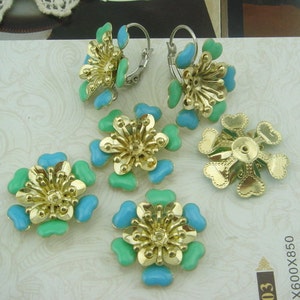 Può includere: Un set di sei decorazioni dorate a forma di fiore con smalto blu e verde. Le decorazioni hanno un centro rialzato e sono perfette per aggiungere un tocco di eleganza a lavori artigianali e gioielli.