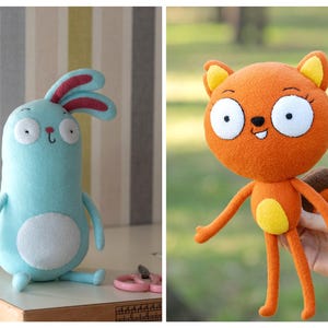 May include: Two handmade plush toys: a light blue bunny with red-lined ears and a white belly, and an orange squirrel with a yellow belly and ears. The bunny sits on a surface, while the squirrel is held up by a hand.
