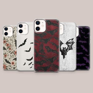 Op de afbeelding: Een verzameling van vijf telefoonhoesjes met verschillende ontwerpen. De hoesjes tonen bloempatronen, vleermuissilhouetten en vleermuis-thema graphics in zwart, rood en wit. De hoesjes zijn ontworpen voor een smartphone.