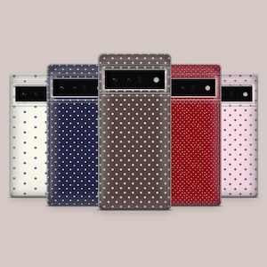 Può includere: Cinque custodie per telefono in fila, ciascuna con un colore e un motivo a pois diverso. I colori includono crema, blu navy, marrone, rosso e rosa. Le custodie hanno un ritaglio rettangolare per la fotocamera nella parte superiore.