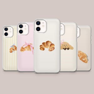 Puede incluir: Cinco fundas para teléfono con diseños de croissant. Las fundas tienen diferentes fondos, incluyendo blanco, rosa y crema. Las ilustraciones de croissant varían, algunas con lazos y caras sonrientes. Las fundas están diseñadas para un smartphone.