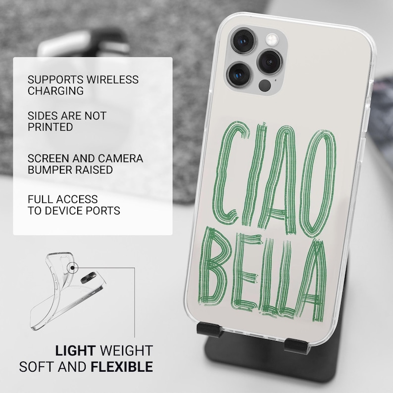 May include: Clear phone case with the words "CIAO BELLA" in green script. The case is on a black stand. The case is light weight, soft, and flexible. It supports wireless charging and has a raised screen and camera bumper.