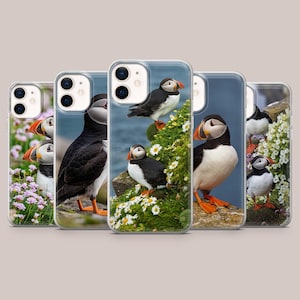 Puede incluir: Una colección de fundas para teléfonos con imágenes de frailecillos. Las fundas muestran las aves en su hábitat natural, con plumaje negro, blanco y naranja. Algunas fundas muestran frailecillos posados en rocas con flores.