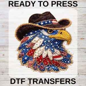May include: A patriotic design featuring an eagle wearing a cowboy hat. The eagle's feathers are decorated with red, white, and blue stars and stripes. The hat is brown with a blue and white band. The text "READY TO PRESS" and "DTF TRANSFERS" are at the top and bottom.