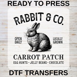 May include: A DTF transfer design featuring a detailed illustration of a rabbit. The design includes the text "Rabbit & Co.", "Carrot Patch", and "Ready to Press". Additional text includes "Open Daily" and "Locally Grown". The design also mentions "Egg Hunts, Jelly Beans, Chocolate".