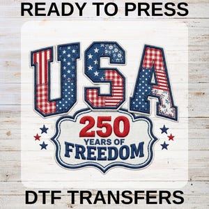 Peut inclure: Un motif de transfert DTF patriotique avec le mot "USA" en lettres patchwork rouges, blanches et bleues. En dessous, une bannière indique "250 YEARS OF FREEDOM". Le motif comprend des étoiles et est placé sur un fond de grain de bois blanc. Le texte en haut dit "READY TO PRESS" et en bas "DTF TRANSFERS".