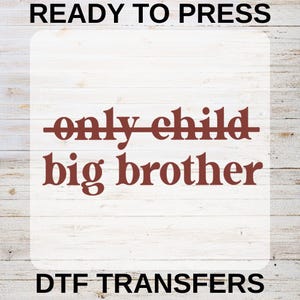 Peut inclure: Transfert DTF avec le texte "READY TO PRESS" en haut et "DTF TRANSFERS" en bas. Le texte principal indique "only child" barré et "big brother" en rouge foncé.